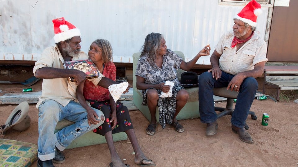 Aborigines sitzen vor ihrer Behausung.