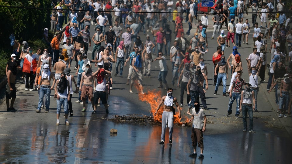 Demonstranten auf der Strasse, brennende Gegenstände.