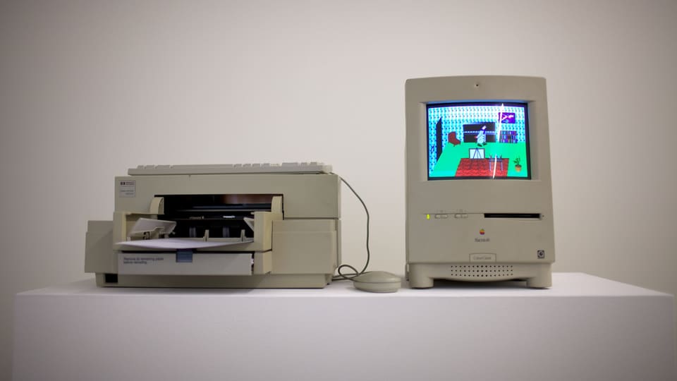 Ein alter Macintosh Desktop-Computer von Apple, auf dem eine Bildschirmgrafik zu sehen ist