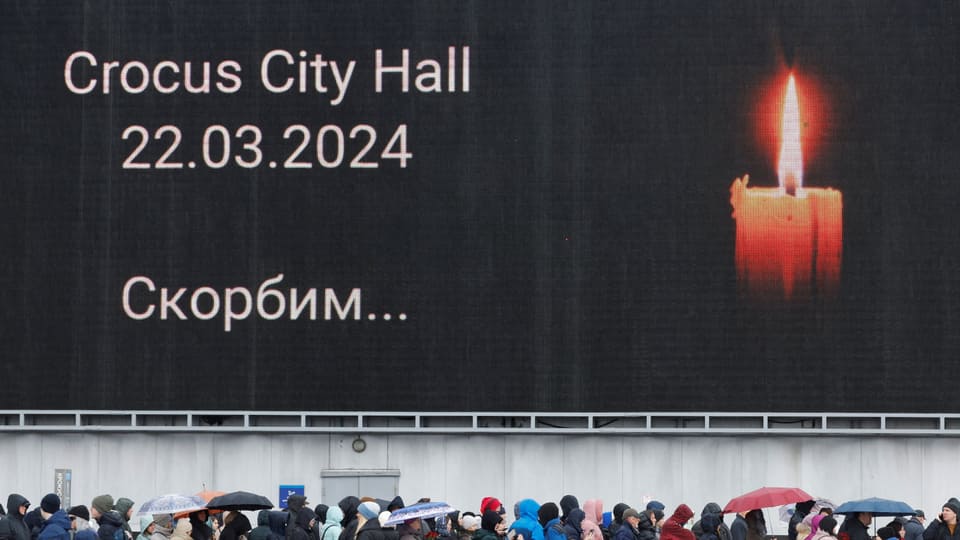 Ein riesiges Plakat mit einer Kerze, darunter Menschen 