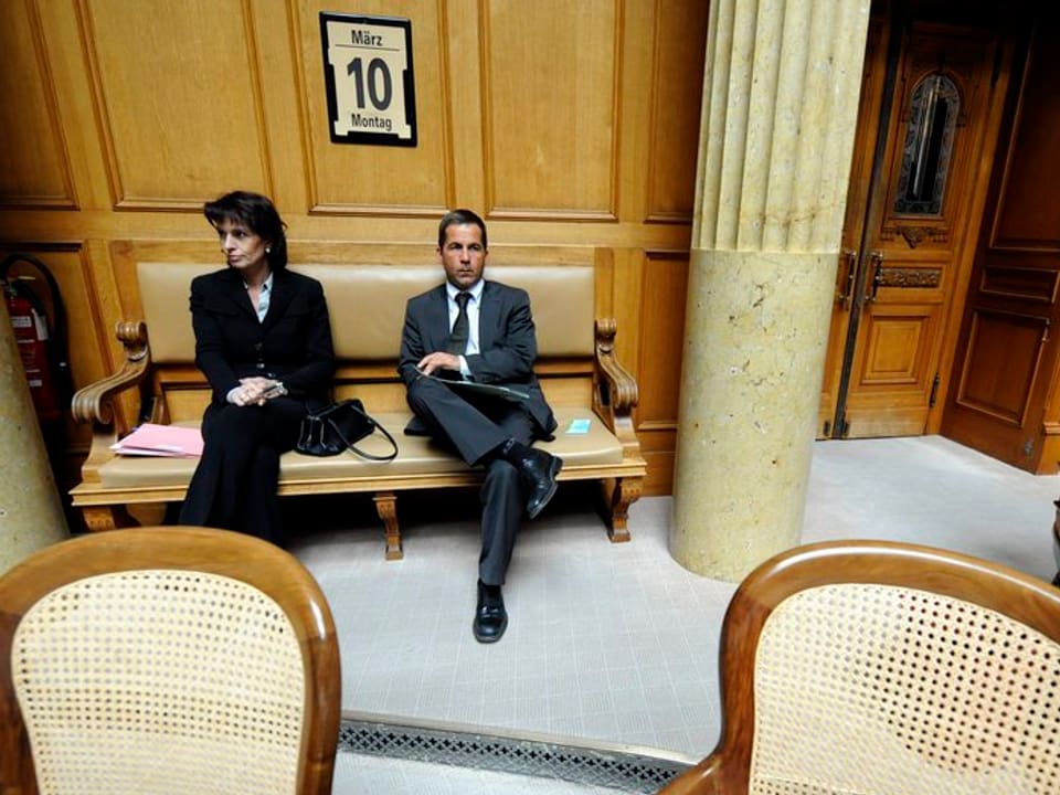 Ein Mann und eine Frau sitzen auf einer Bank zuhinerst im Nationalratssal.