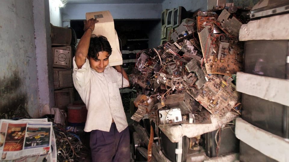 Ein Mann in Indien steht in seinem Laden voller E-Waste, also Elektroschrott.