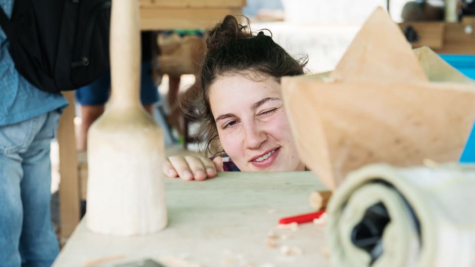 Eine junge Frau schielt auf eine Holzskulptur