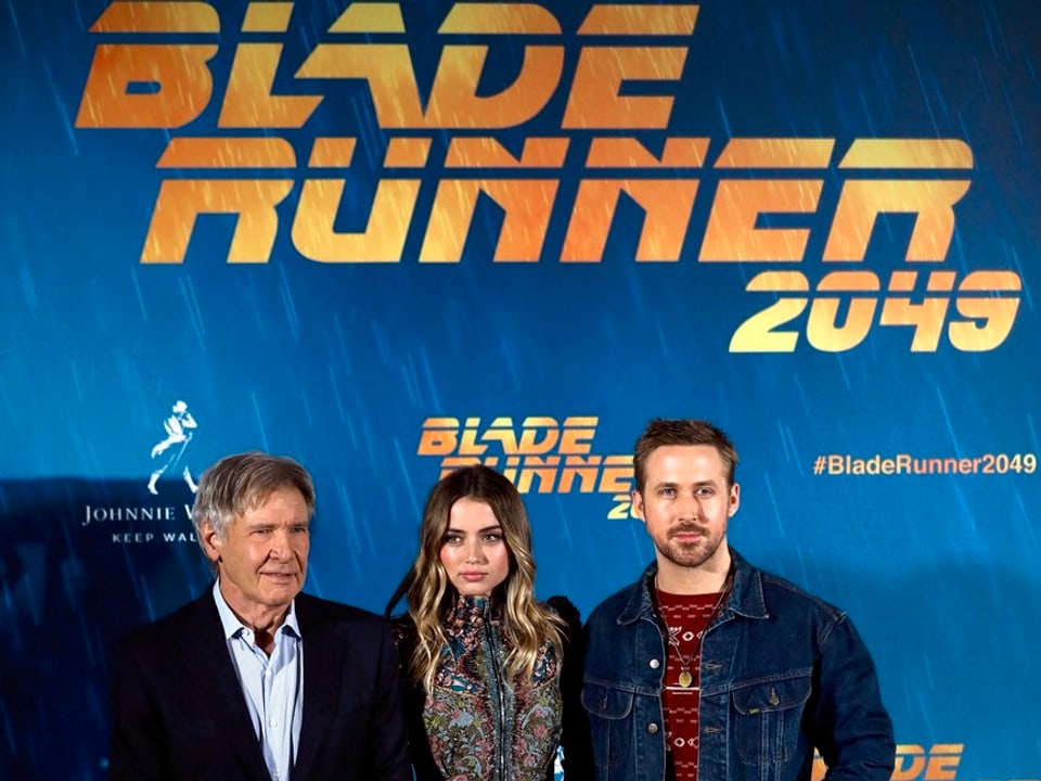 Harrison Ford, Ana de Armas und Ryan Gosling posieren vor einer blauen Fotowand. 