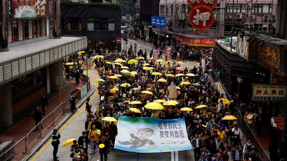 Menschen mit gelben Schirmen auf den Strassen Hongkongs