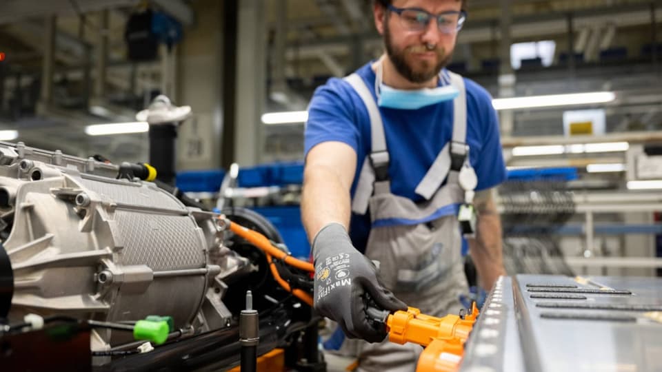 Ein Arbeiter hantiert an einem Kabel neben einer grossen Metallspule