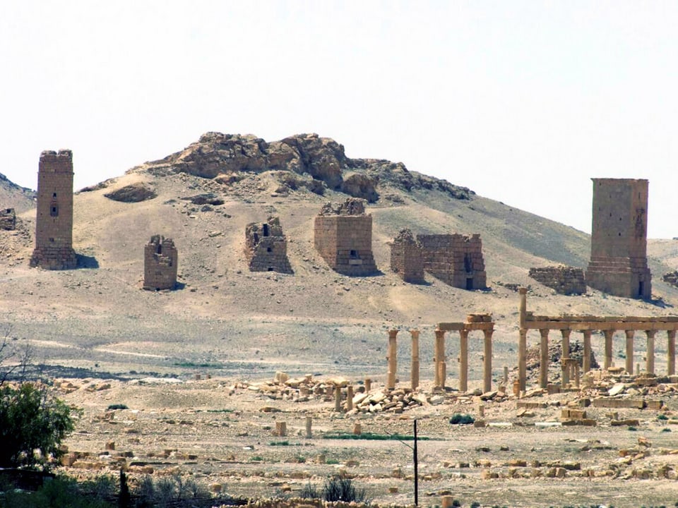 An einem Hügel in einer Wüstenlandschaft befinden sich 8 zum Teil gut erhaltene, grosse Steintürme.