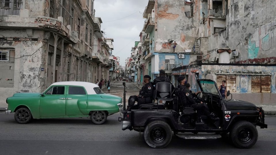 Jeep mit Soldaten in Strassen von Havanna, en Oldtimer daneben