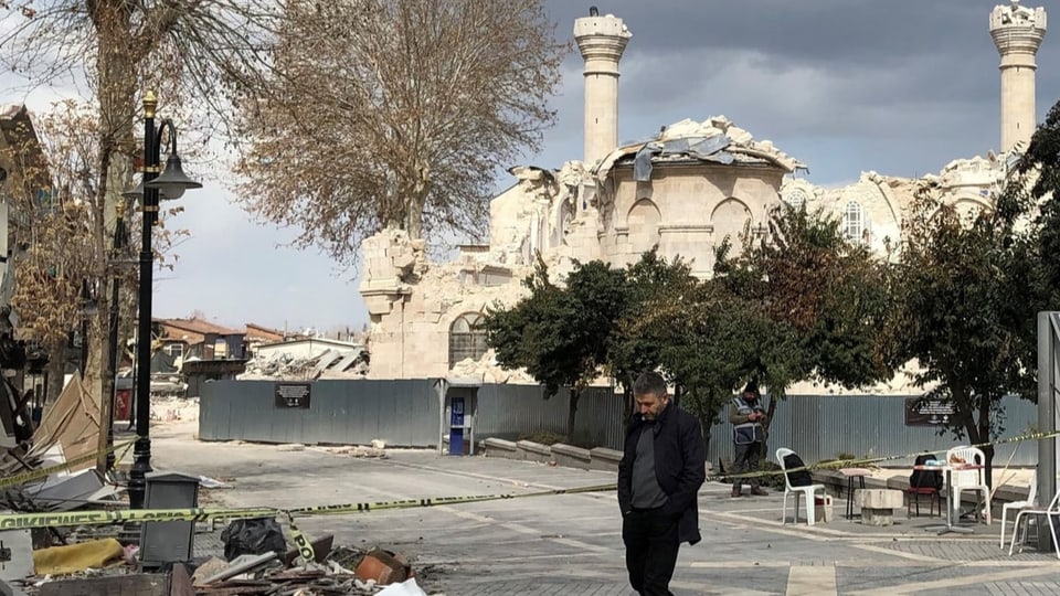 Mann läuft an zerstörter Moschee vorbei.