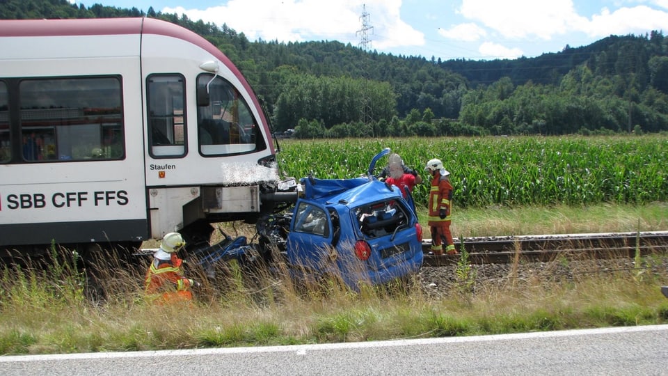 Ein Regionalzug der SBB. Vor dem Zug ist ein stark beschädigter Personenwagen.