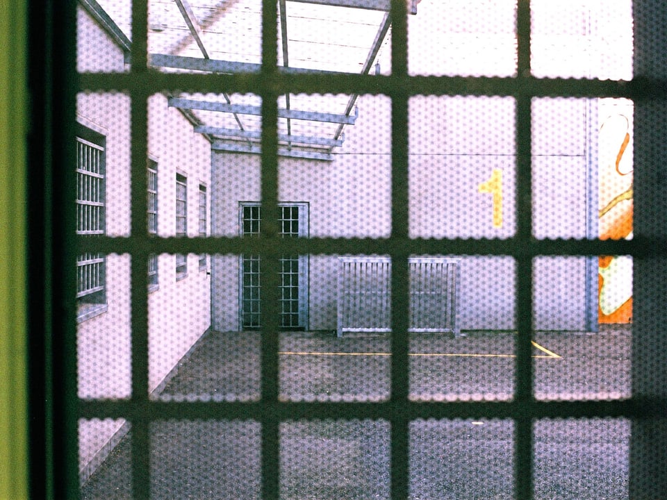 Blick durch ein vergittertes Fenster auf den Spazierhof des Gefängnisses Bässlergut.