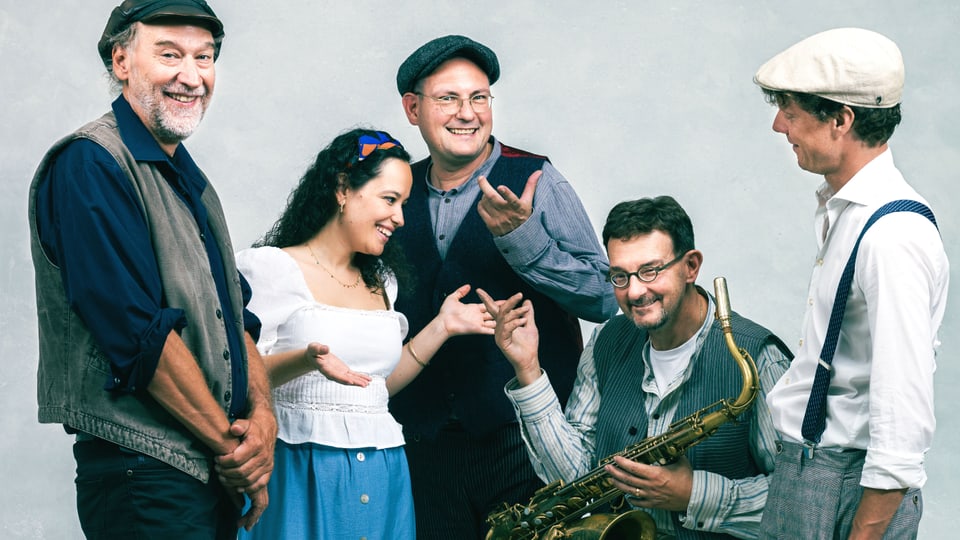 Vier Männer, einer hält ein Saxophon und eine Frau