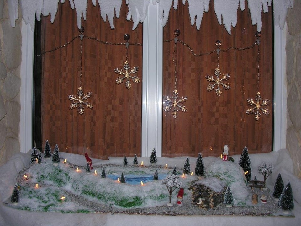 Adventsfenster mit verschneiter Landschaft.