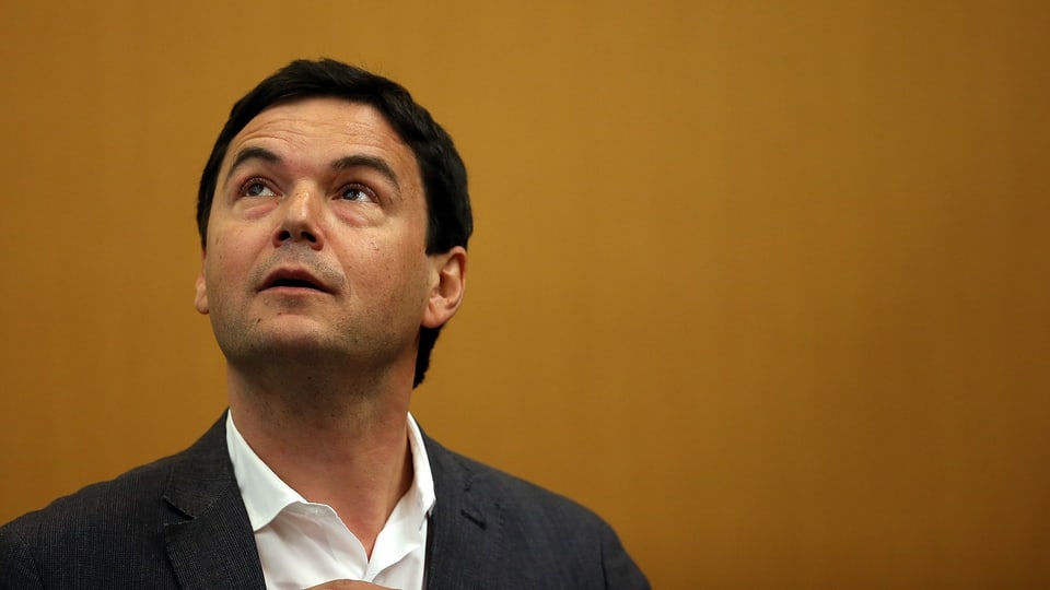 Thomas Piketty schaut nach oben. Er trägt einen Anzug.