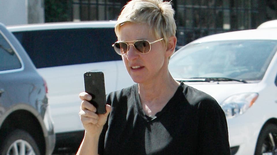 Ellen DeGeneres mit Sonnenbrille und einem schwarzen «iPhone» in der Hand.