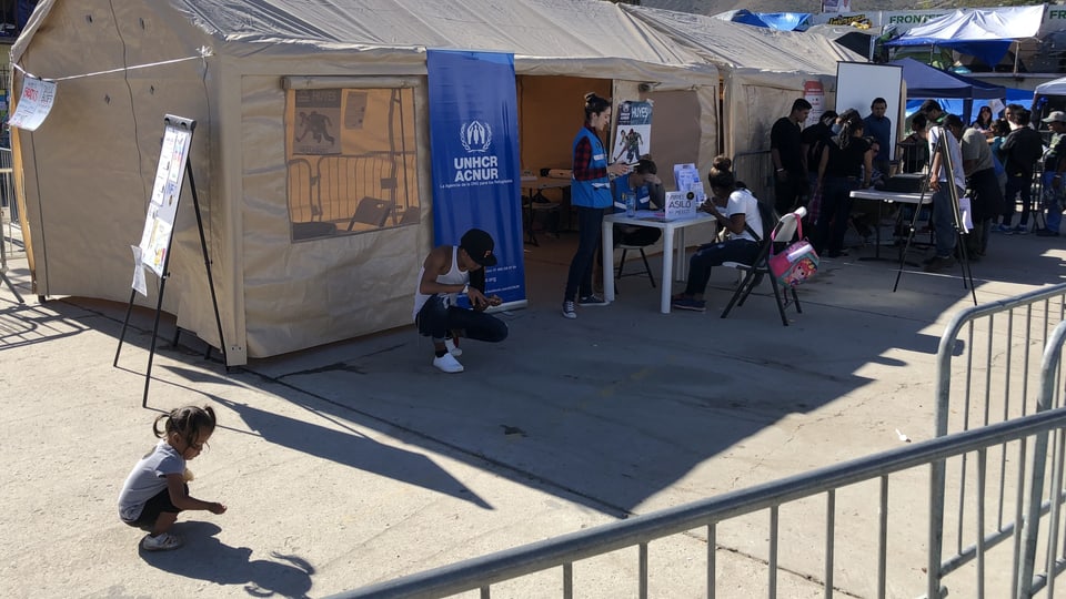 Kinder spielen vor einem Zelt des UNHCR.