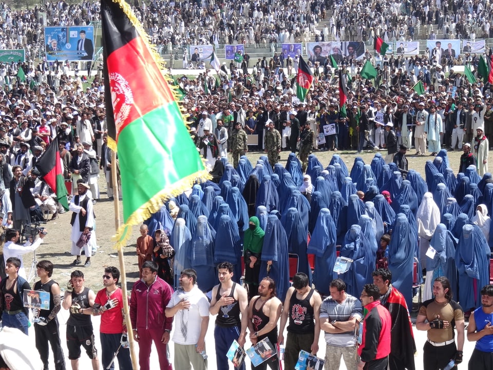 Hunderte Männer und Frauen in einem Fussballstadion, die Frauen in meist blauen Burkas.