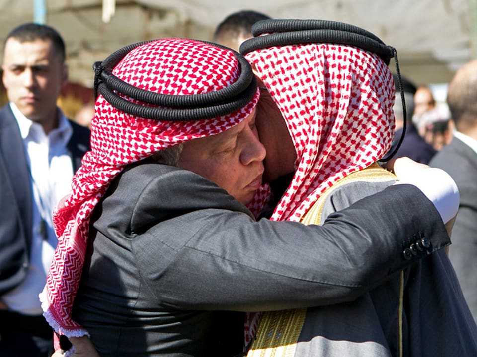 König Abdullah umarmt den Vater des Opfers. Beide haben eine traditionelle Kufya.