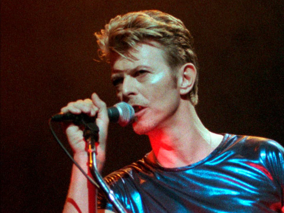 David Bowie in Glitzershirt auf der Bühne.