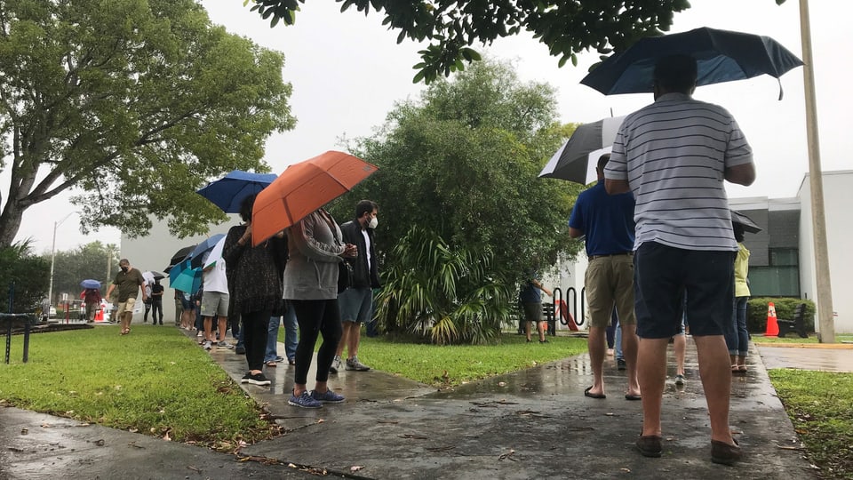 Menschen stehen Schlange mit Regenschirmen