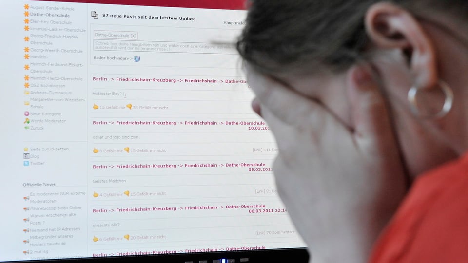 Ein Mädchen mit Ohrring sitzt vor einem Computerbildschirm und hält die Hände vors Gesicht.
