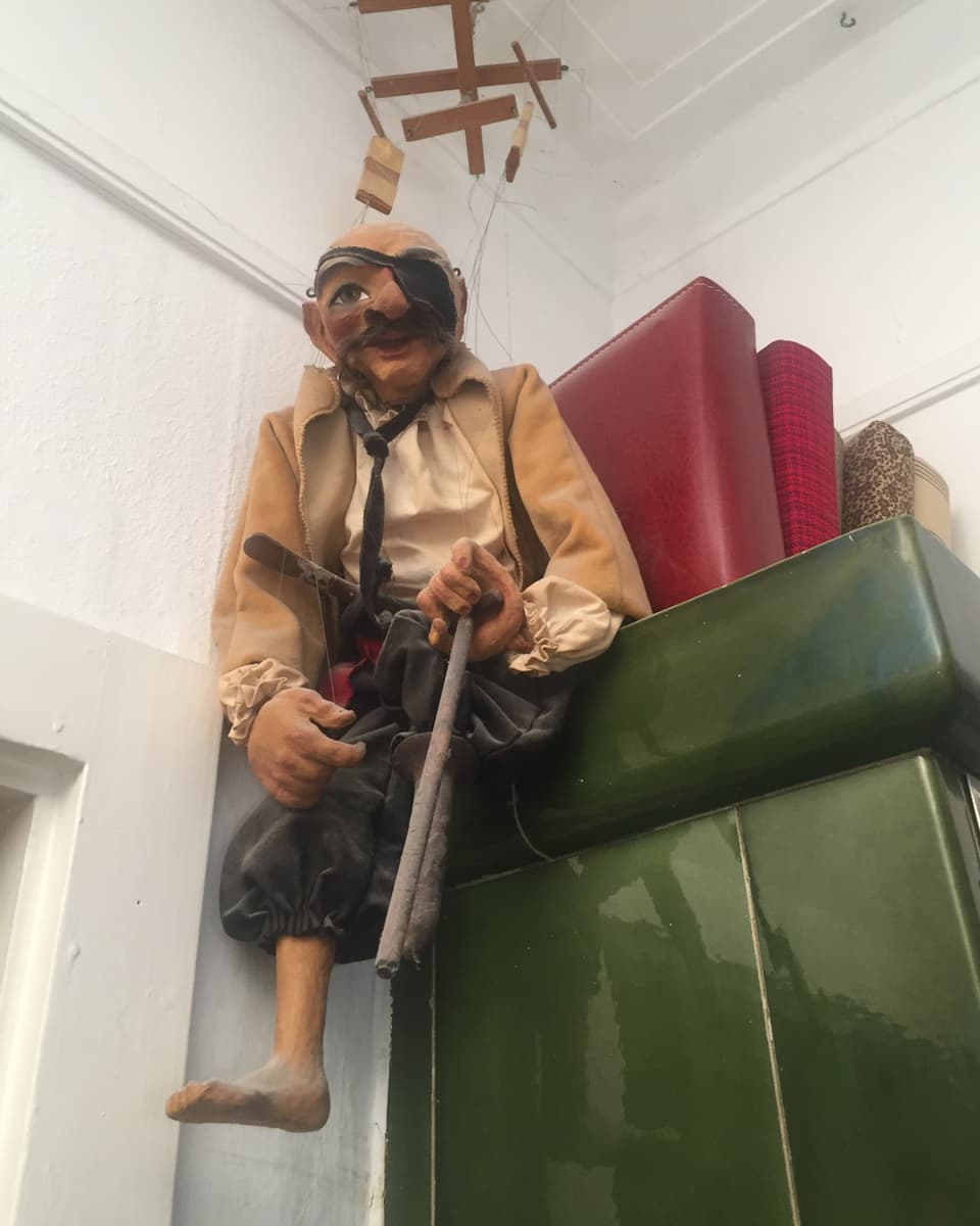 Eine auf einem Kachelofen platzierte Marionetten-Figur.