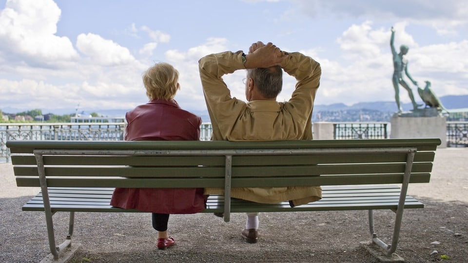 Eine alte Frau und ein altern Mann sitzen auf einer Bank. 