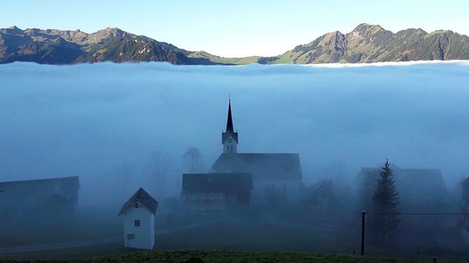 Kirche im Nebel, darüber Sonnenschein