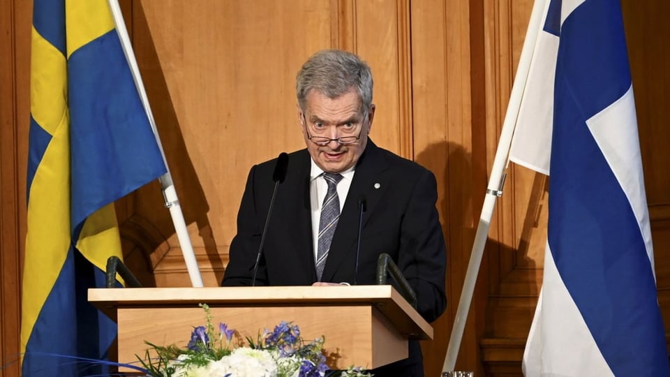 Finnlands Präsident Sauli Niinisto neben einer Flagge Finnlands und Schwedens.