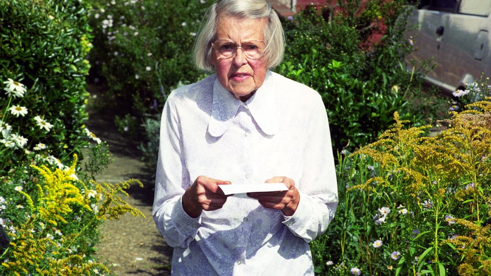 Alte Frau im Garten mit Brief