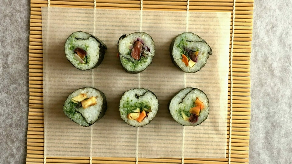 6 Sushi mit Wurzelgemüse statt Fisch auf einem Sushi-Mättchen aus Bambus.