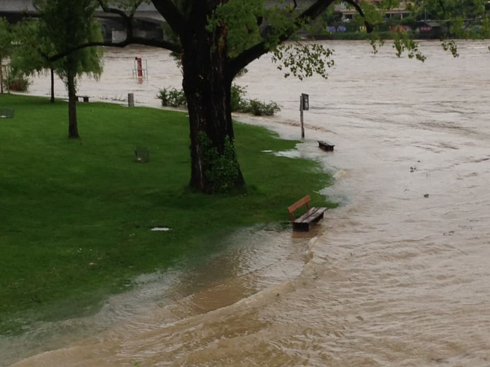 Der Rhein in Basel ist über die Ufer getreten. Eine Sitzbank steht im Wasser.