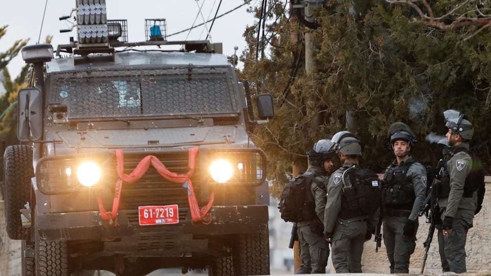 Angehörige der israelischen Armee stehen neben einem Militärfahrzeug.