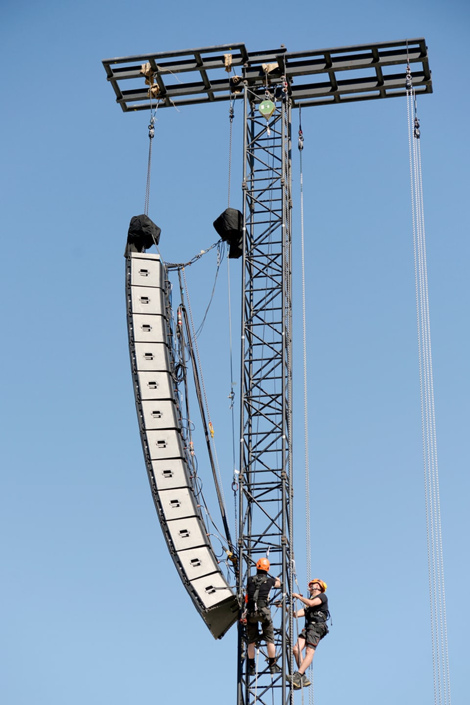 zwei Menschen klettern mit einer Lautsprecherreihe auf einem Mast herum