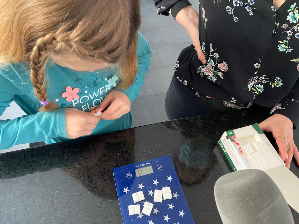 Annina und Ladina wägen die Gramme Zucker mit Zuckerwürfelchen ab. 