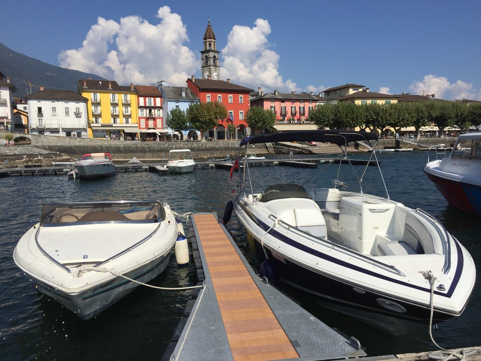 Zwei Motorboote bei Ascona mit farbigen Häusern im Hintergrund.