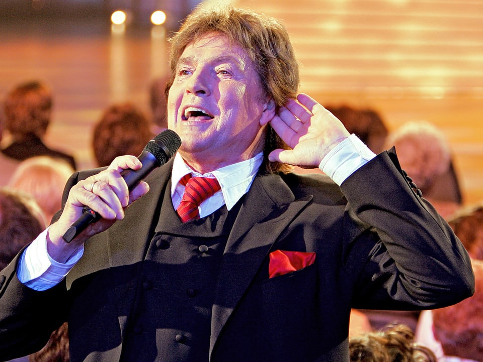 Ein Sänger im Anzug bei einem Auftritt.