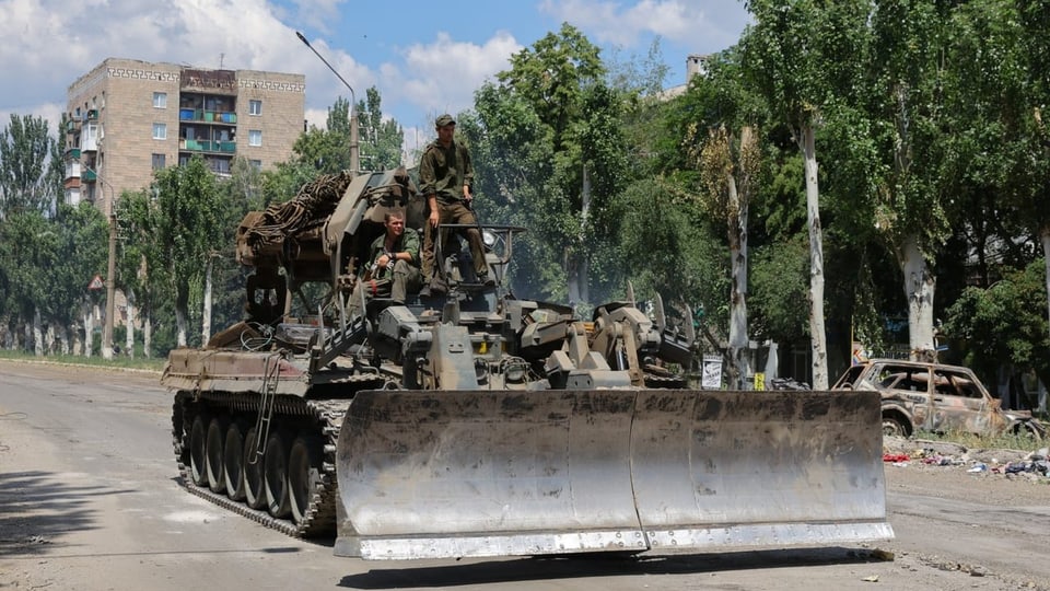 Angehörige pro-russischer Truppen fahren mit einem Raupenfahrzeug. 