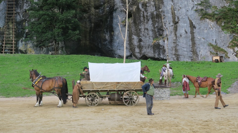 Theaterszene im Freien mit Pferden und Planwagen. 