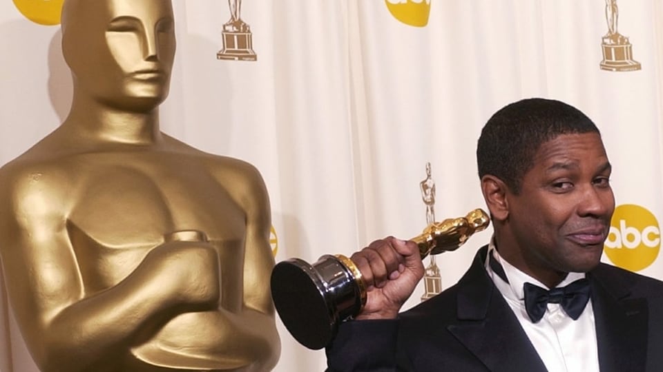 Denzel Washington hält den Oscar in der Hand.