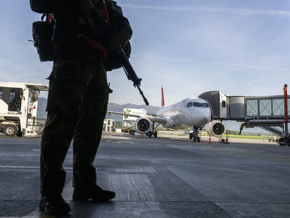 Ein bewaffneter Soldat steht in der Nähe eines Flugzeugs.