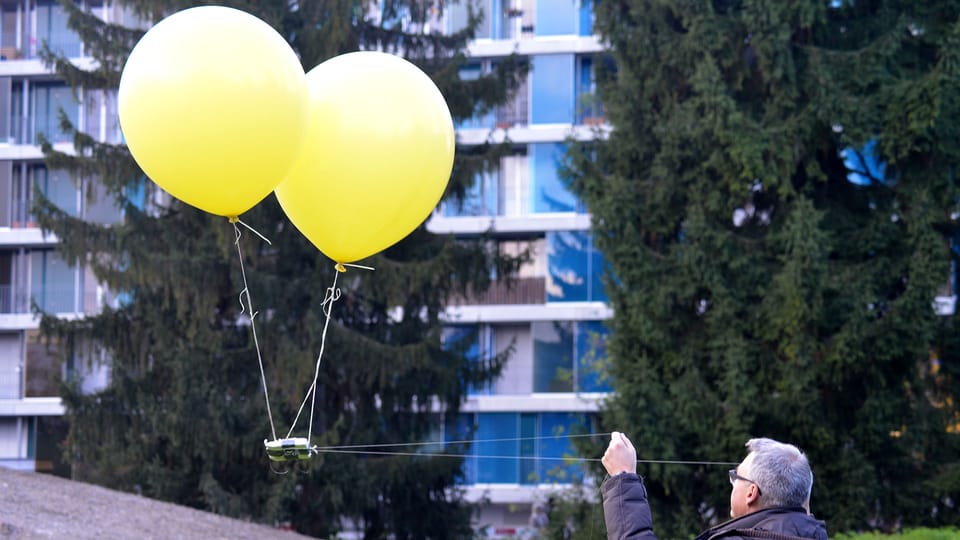 Das Bild zeigt Digitalredaktor Peter Buchmann, der mit zwei Schnüren zwei Luftballone steuert, unter denen eine Kamera befestigt ist. 