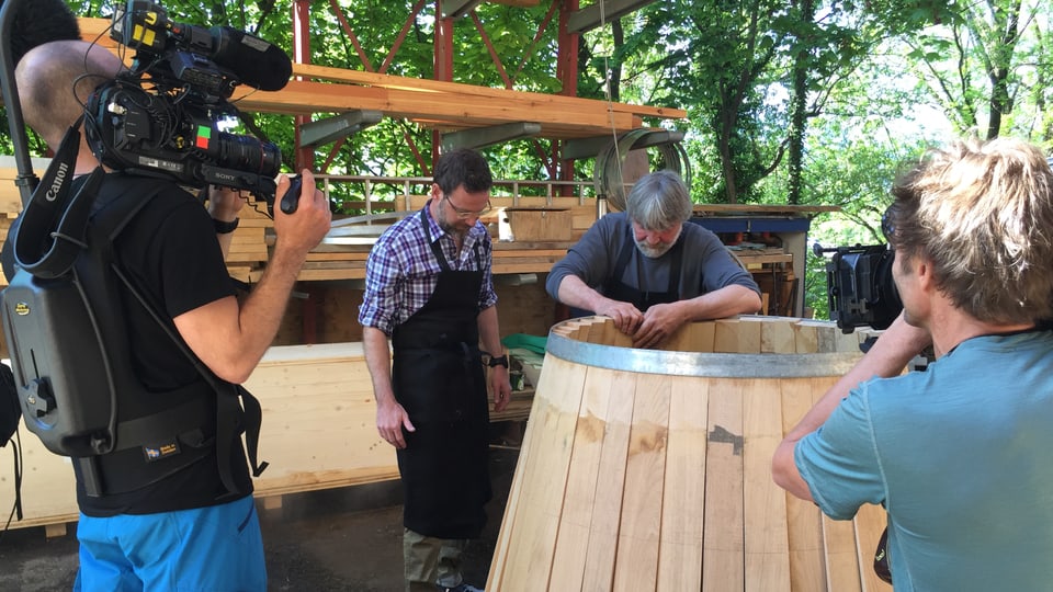 Kamerateam filmt Nik und den Küfer bei der Arbeit mit einem Holzfass. 