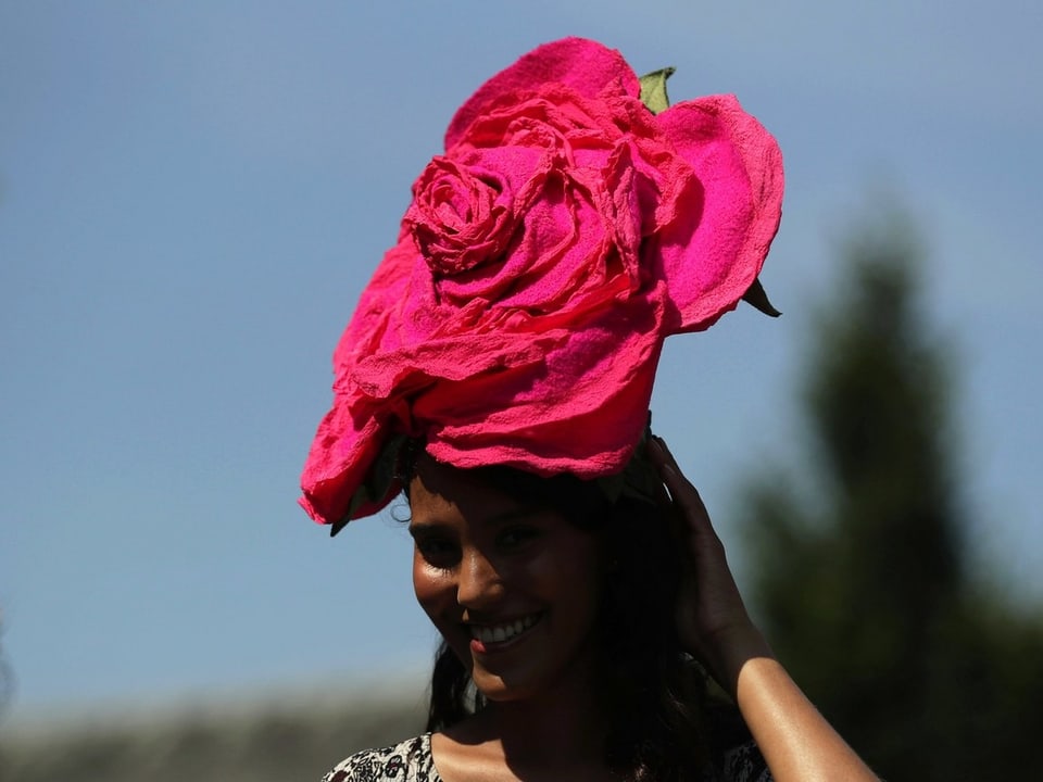 Eine Frau mit Hut in der Rorm einer Rosenblüte.