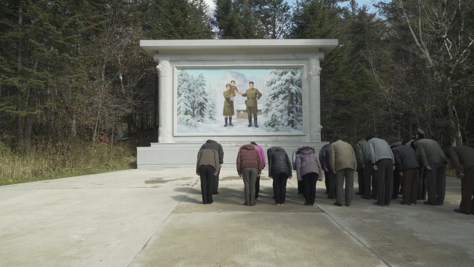 Menschen verbeugen sich vor einem Monument
