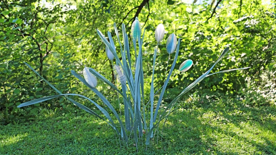 Blumen aus Plastik stecken in einer Wiese