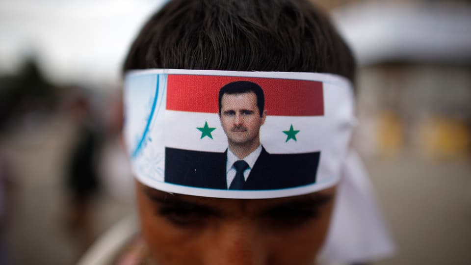 Ein Mann trägt eine Kopfbinde mit dem Porträt Assads.