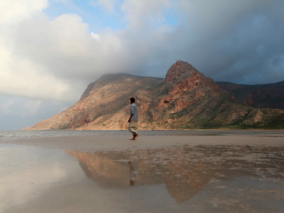 Ein Mann läuft einen Strand entlang.