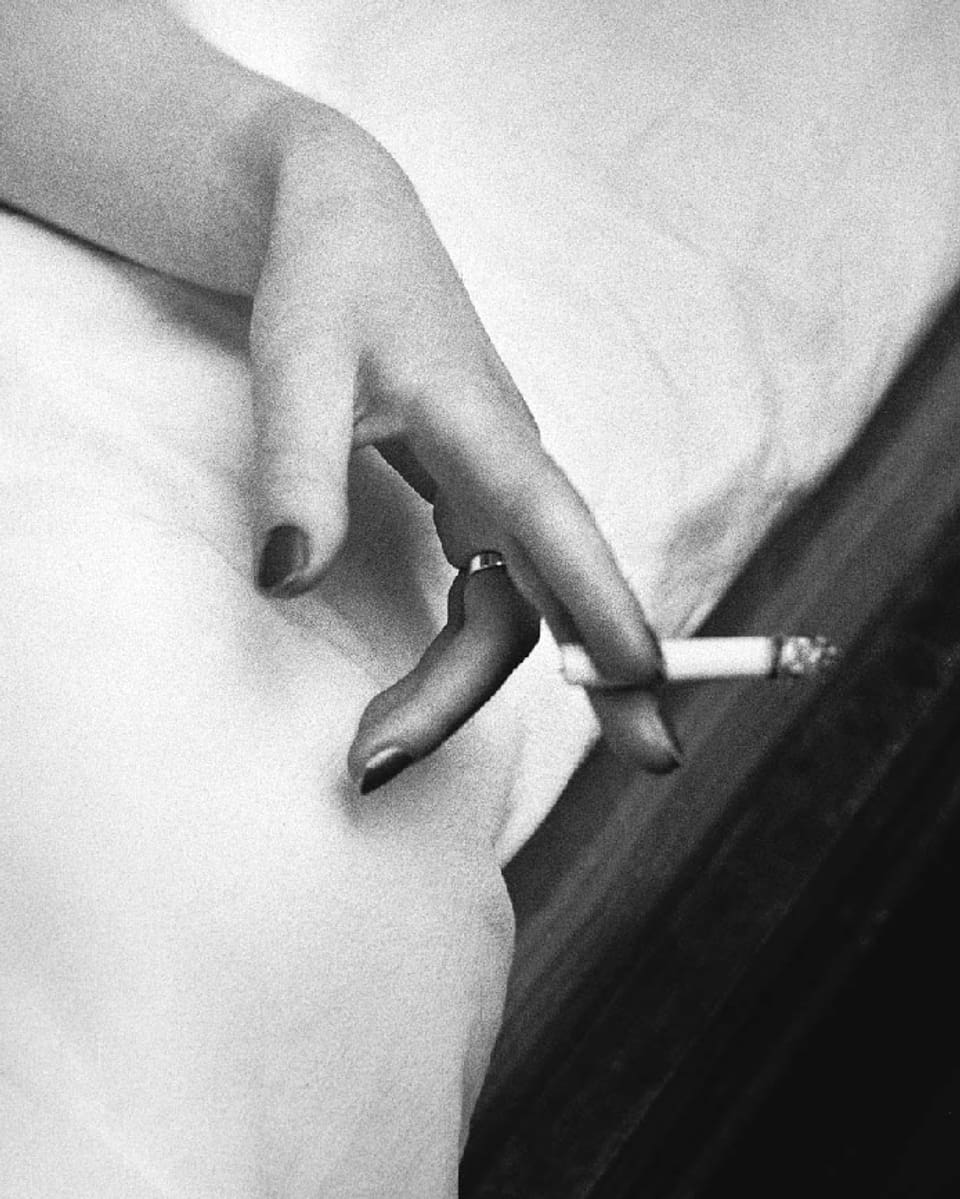 Eine weibliche Hand mit lackierten Fingernnägeln hält eine Zigarette.