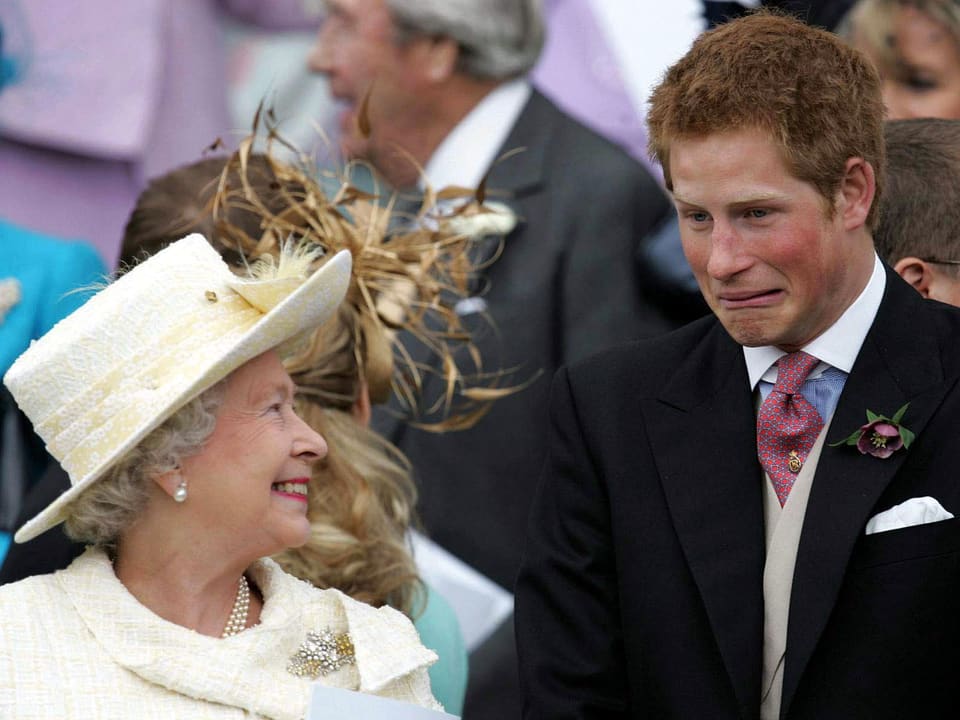Die Queen lächelt Prinz Harry an, der eine Grimasse schneidet.